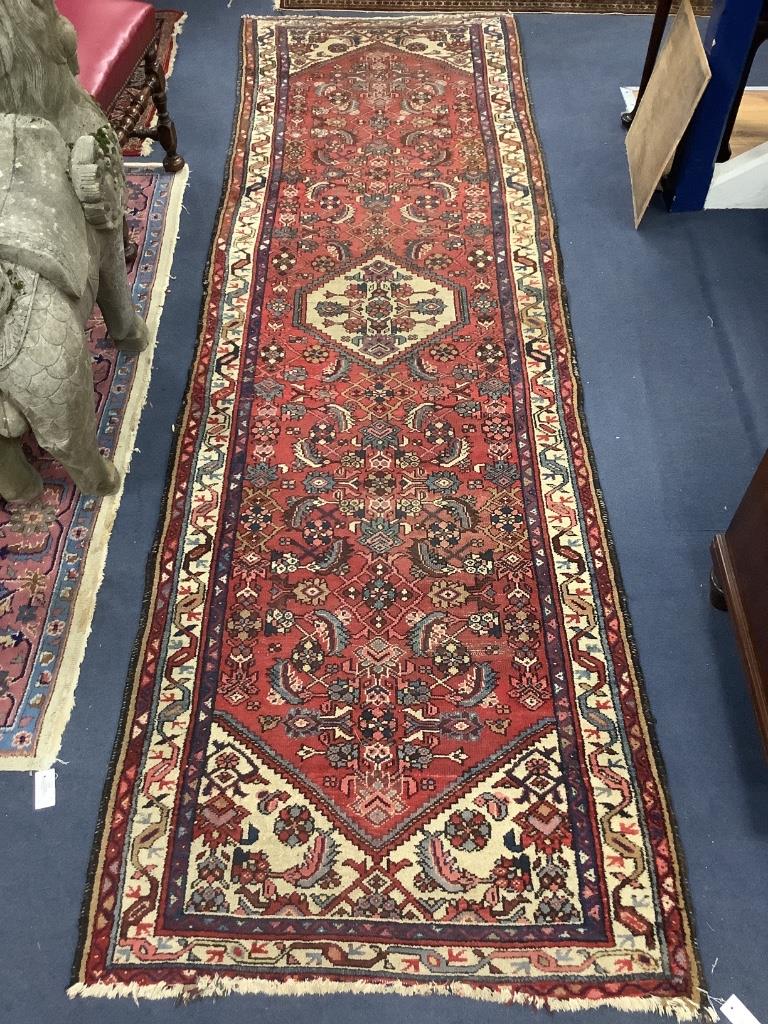 A Caucasian red ground hall carpet, 340 x 102cm